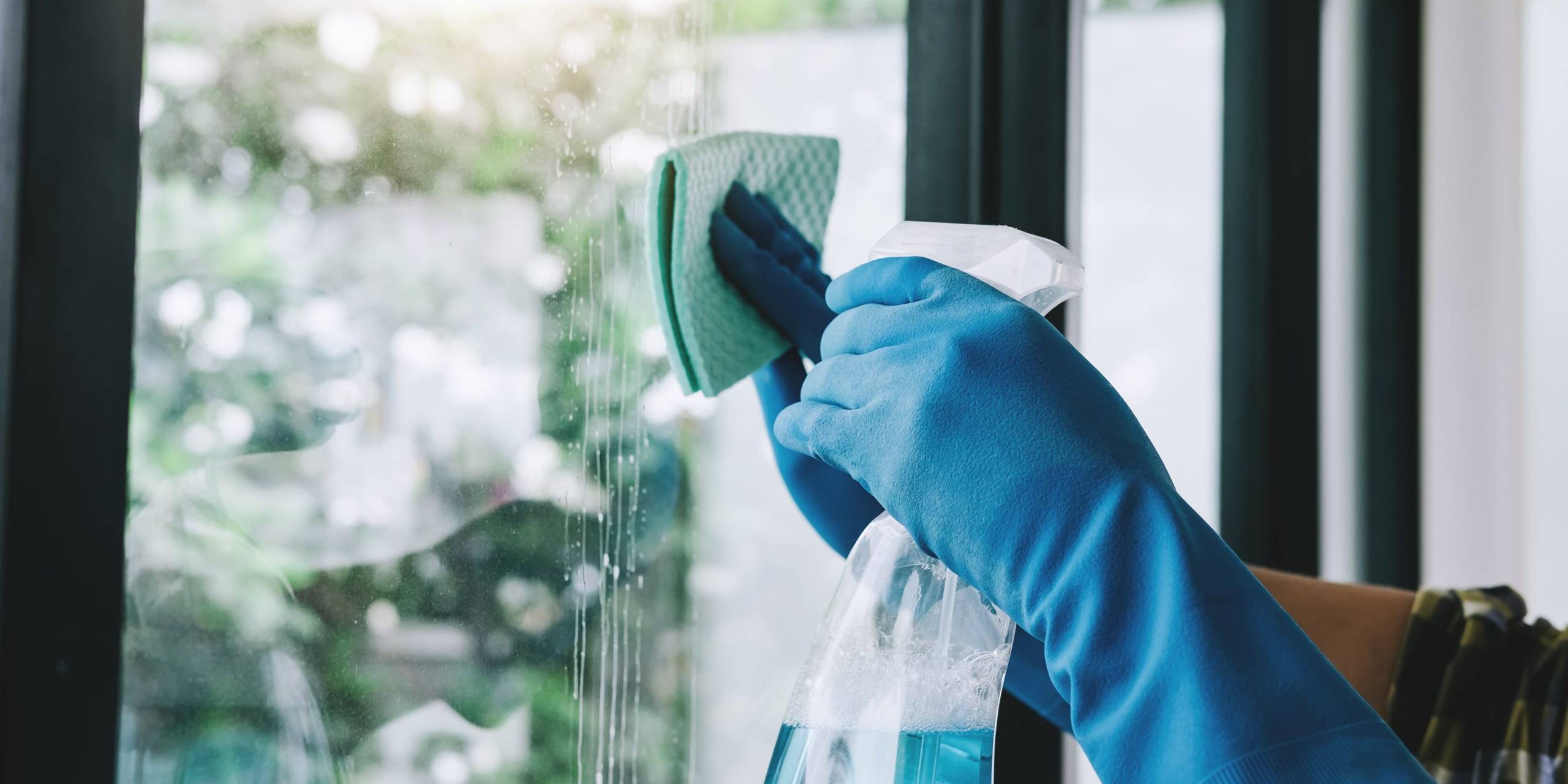 person cleaning window with spray and cloth