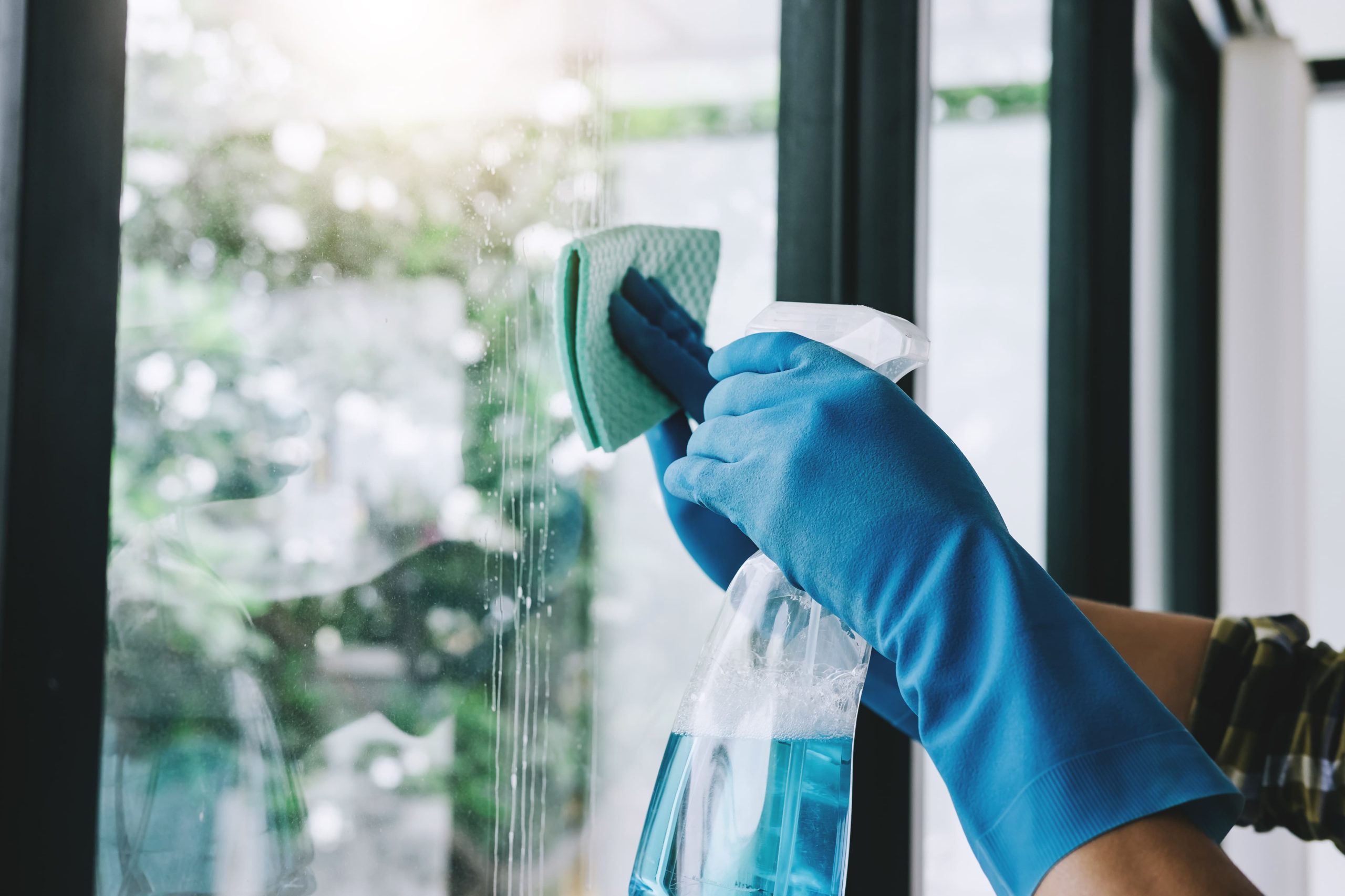 person cleaning window with spray and cloth