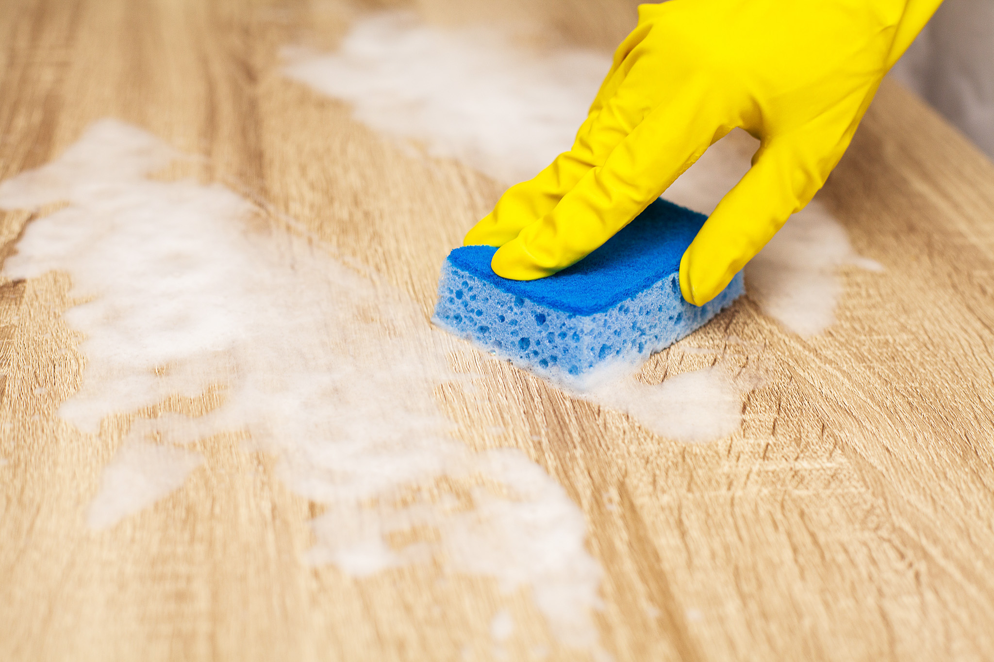 Employee using sponge for cleaning wood table.